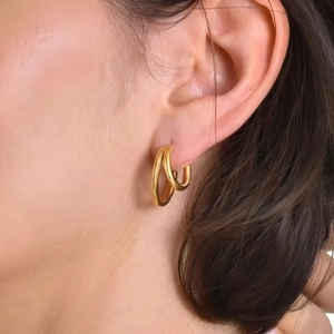 Minimalistische doppellagige C-förmige Goldene Creolen am Ohr eines Models