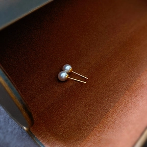 Close-up of elegant white round pearl earrings on a dark brown velvet texture background