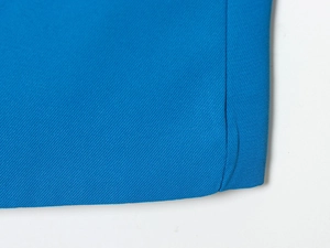 Détail macro du tissu sergé bleu montrant des coutures fines sur le coin du costume