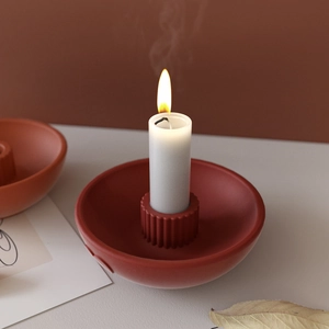 Detail view of a dark red matte ceramic candle holder with vertical striped texture