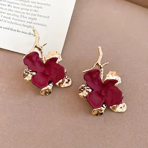 Elegant deep red matte flower drop earrings with golden accents on a warm beige background