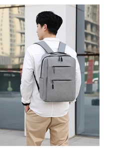 Grey business laptop backpack with USB port shown being worn by a model in a city setting