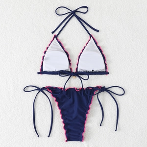Two-piece halter bikini set in navy blue with vibrant pink ruffled trim on plush background