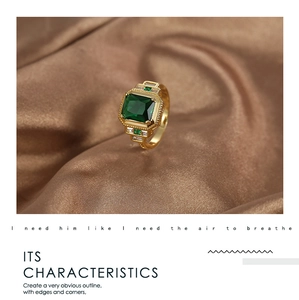 Macro detail of emerald cut green zircon ring with small diamonds on gold silk background