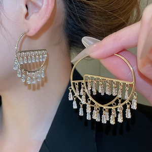 Detail of elegant gold tassel earrings featuring trapezoid zircons worn by model