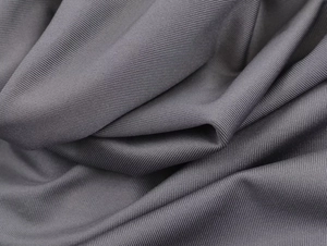 Detailed macro view of dark grey fabric texture with fine twill weave and elegant drape