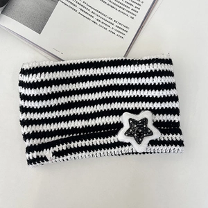 Detailed knit texture of striped cat ear beanie with sequined star patch and pom-poms