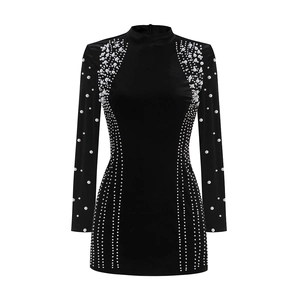 Détail d'une mini robe noire à col montant avec perles blanches et ornements de strass