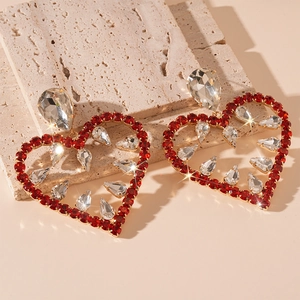 Detailed close-up of hollow heart earrings with red and clear crystals on stone