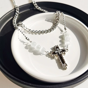 Detail of silver double-layered necklace with cuban chain, white beads and cross pendant