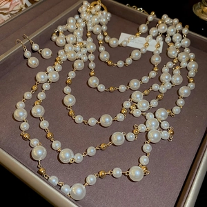Detailed shot of multilayered pearl necklace and earrings set in a vintage display tray