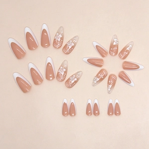 Faux ongles amande french avec motifs floraux blancs et accents élégants de perles
