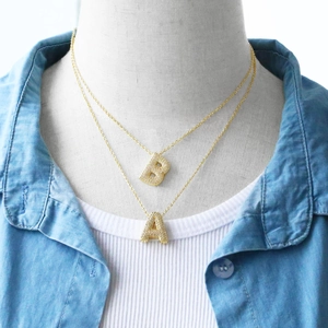 Detail of gold letter necklaces A and B with micro-pave cubic zirconia on models