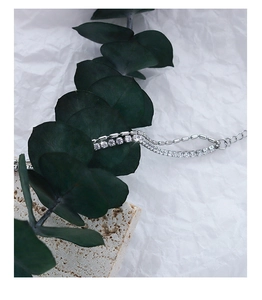 Macro detail of silver layered bracelet with cubic zirconia tennis chain and metal beads