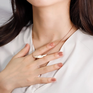 Detail of rose gold feather pendant necklace showing fine textures on the collarbone