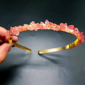 Close-up of handmade pink crystal chips on golden wire headband with dark background