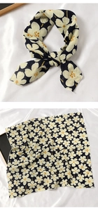 Détails d'un foulard en coton noué et à plat avec des motifs floraux crème sur fond noir
