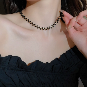 Nahaufnahme einer vergoldeten Kette mit schwarzen Perlen an einem weiblichen Model