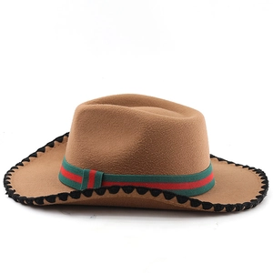 Detail of a brown felt cowboy hat with red and green striped band and braided brim edge