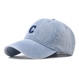 Détail d'une casquette en denim délavé bleu clair avec broderie de la lettre C en bouclée