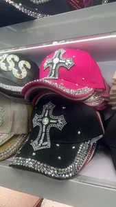 Detailed view of pink and black satin baseball caps featuring rhinestone cross patterns