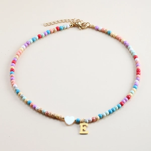 Close-up of colorful stone beaded necklace with white heart and gold letter E pendant