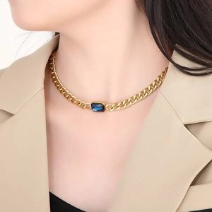 Detail van gouden Cubaanse schakelketting met rechthoekig blauw kristal op een model