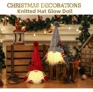 Detail of two Christmas glowing gnomes with knitted hats and warm LED lights on a mantel