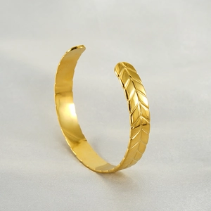 Detail view of 18K gold-plated stainless steel cuff featuring embossed wheat patterns