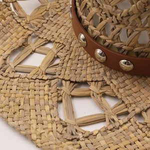 Détail d'un chapeau de paille tressé avec bandeau en cuir marron et rivets argentés