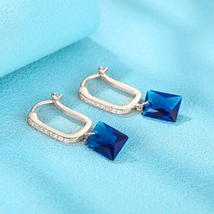 Macro shot of U-shaped silver earring with square deep blue crystal and small diamonds