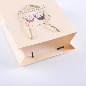 Close-up of cream gift paper bag with golden spiral handles and cartoon printing