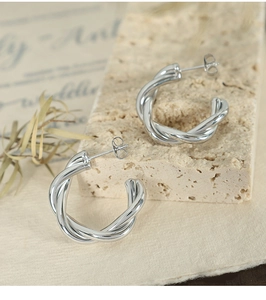 Close-up of silver braided twist hoop earrings on elegant textured stone background