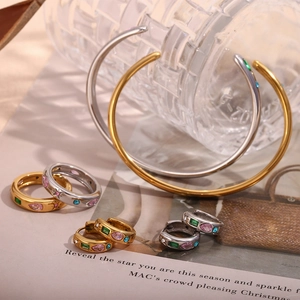 Close-up of 18K gold and silver rings with colorful zircon gemstones on text paper