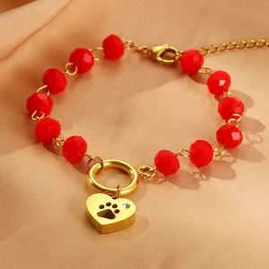 Detail of red faceted beads bracelet with gold heart paw print charm on silk background