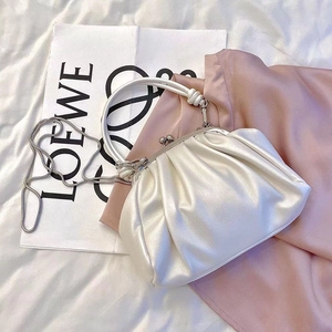 Close-up of a pearl white pleated dumpling bag with elegant metal clasp and chain strap