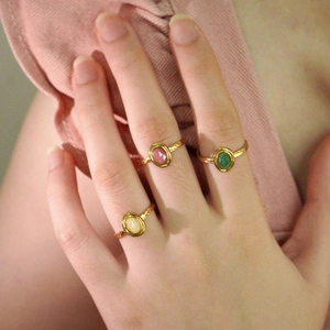 Close-up of gold-plated rings with colorful oval natural stones on a model's hand