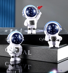 Tre figurine di astronauti in resina con bandiera rossa e stella sopra i libri