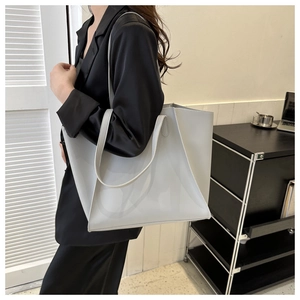 Lifestyle view of a large light grey faux leather tote bag worn over the shoulder