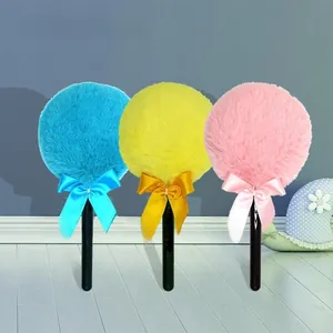 Detail of plush fairy wand powder puffs in blue, yellow, and pink with ribbon bows