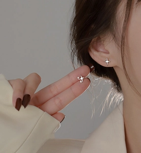 Close-up of minimalist silver four-point star earrings worn on a model's earlobe