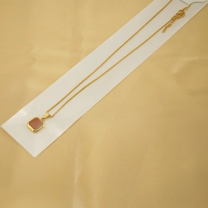 Détail du collier à pendentif carré en acier titane plaqué or 18 carats sur soie dorée