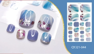 Macro detail of ocean-themed toe nail wraps with glitter, seashell charms and rhinestones