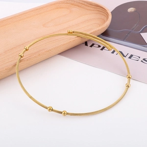 Detailed view of a gold-toned twisted wire choker necklace with minimalist bead accents