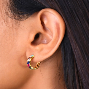 Close-up of rainbow hoop earrings with colorful square-cut stones on a model's ear