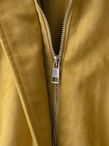 Macro detail of high-quality metal zipper on ocher faux suede bomber jacket