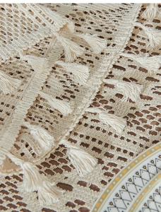 Detailed macro shot of beige woven lace table runner with fringe on dark wood