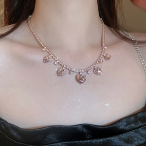 Detail of gold necklace with pink heart gems and clear rhinestones on neck