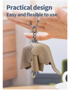 Macro detail of beige leather elephant keychain with metal ring being held by hand