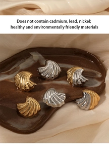 Macro detail of shell-shaped stainless steel earrings in gold and silver finishes